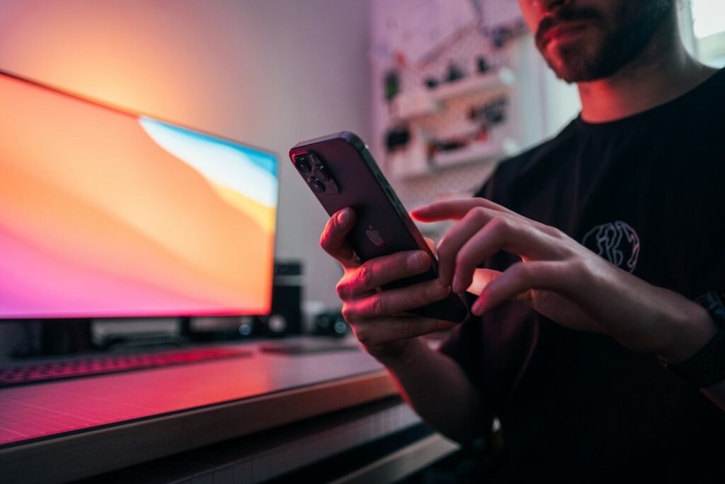 Person holding smartphone at desk; illustrative and not the OnlyFans interface