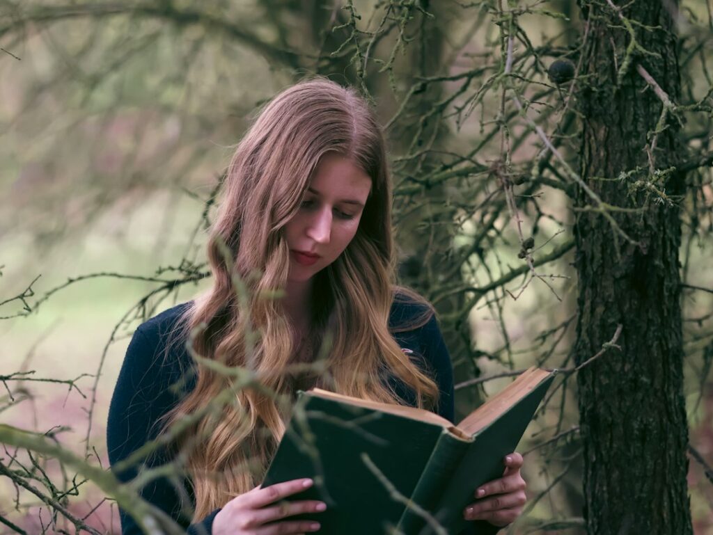 Person reading a book in woodland; not Sarah J Maas or the ACOTAR book cover